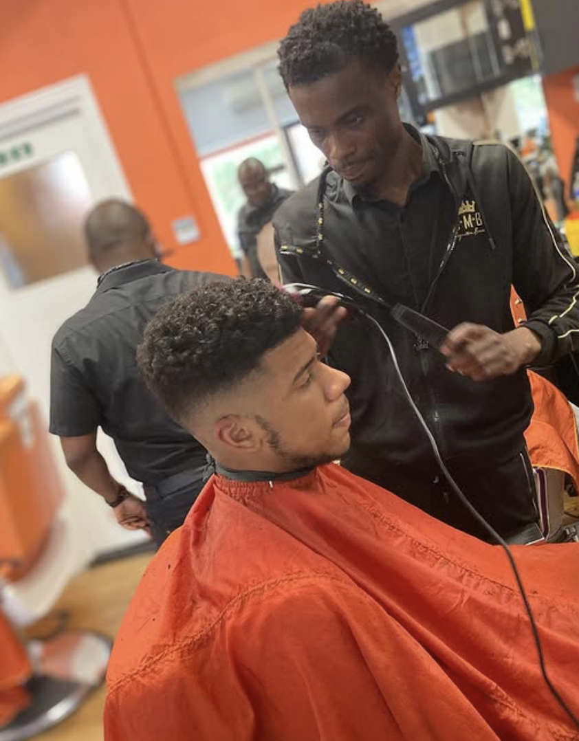 Barber working inside the Extreme Kutz shop in St Albans